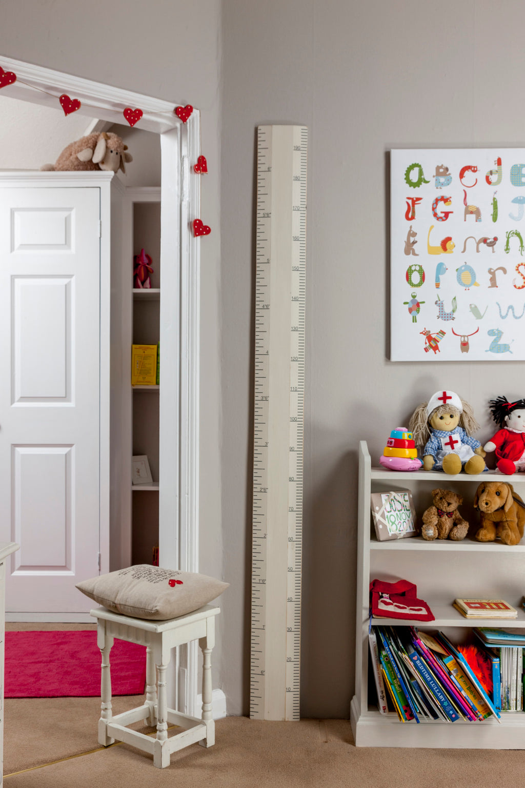 Children's room with a growth chart, books, toys, and alphabet poster.