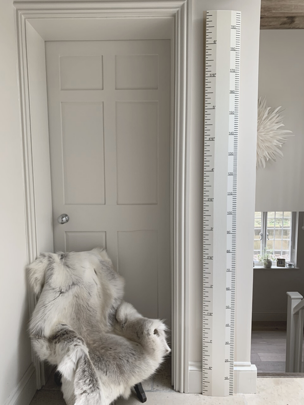 Room interior with a door, fur throw, and tall decorative ruler.