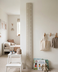 Nursery room with height chart, books, and toys on a white wall.